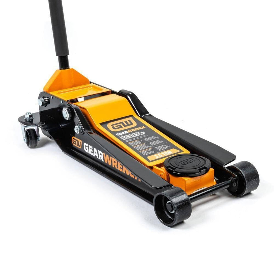 image 3.5 Ton Low Profile Floor Jack. 
The image shows a low-profile floor jack, primarily in black and orange, with the brand "Gearwrench" visible on its side and top. It has a long handle extending upwards from the rear, and four wheels, one at each corner of its rectangular base.