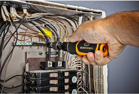 An electrician using the Gearwrench 89620 torque screwdriver to precisely tighten a terminal connection inside a complex electrical panel, demonstrating the tool's application in professional service and assembly.