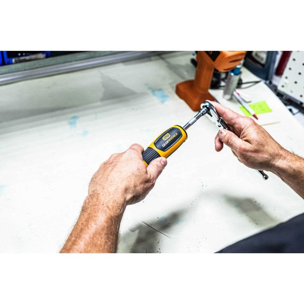 An assembly worker using a Gearwrench ratcheting wrench to adjust the settings on the torque screwdriver handle, demonstrating the tool's integrated 1/4 inch drive tang for easy calibration and adjustment.