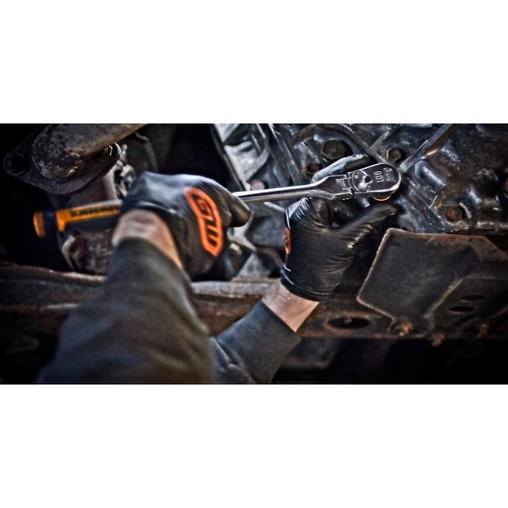 An under-car action shot of a technician wearing black protective work gloves while maneuvering the adjustable flex head of a Gearwrench long alloy steel manual ratchet to turn a hidden transmission chassis fastener.