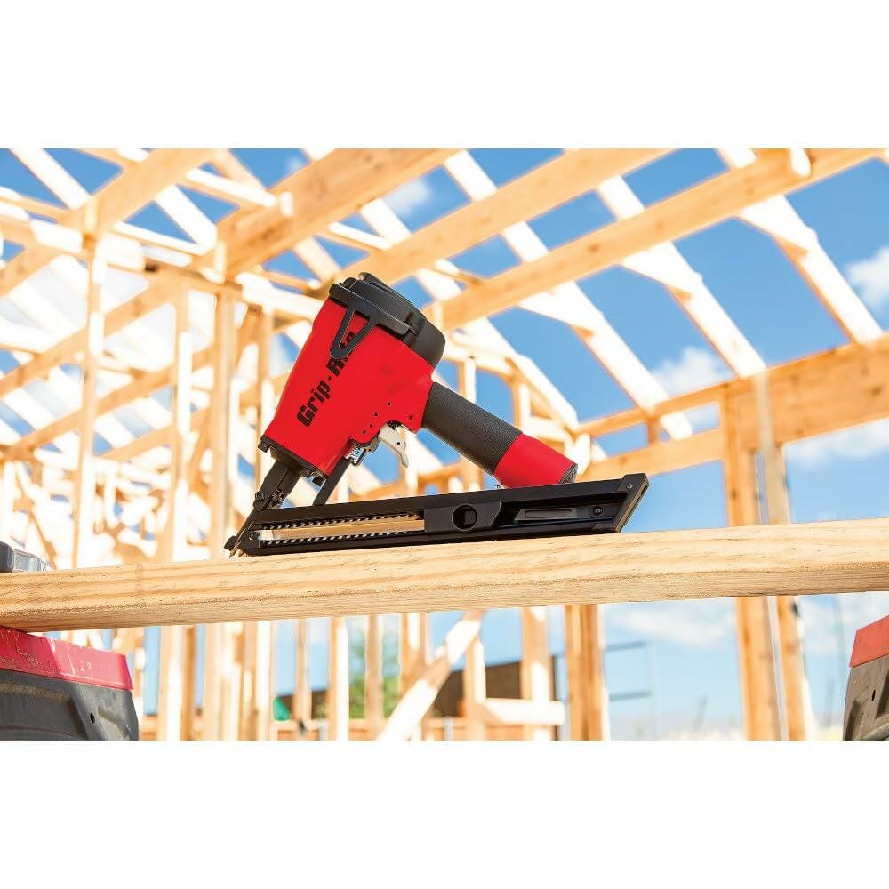 Grip-Rite GRSB150 nailer resting on a wooden beam at a construction site; background shows a framed wooden structure under blue skies, emphasizing the tool’s real-world application in joist hanger installation.
