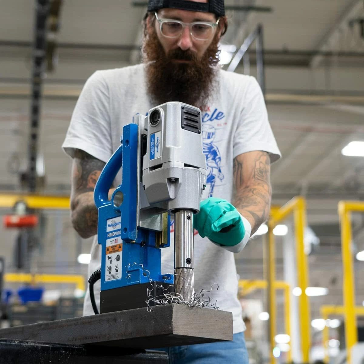 A fabricator using the Hougen HMD900 magnetic drill on a steel workpiece producing metal shavings.