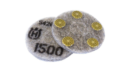 Circular Husqvarna polishing pads shown side by side. One pad features four yellow resin-bonded abrasive segments arranged in a square pattern for surface contact. The other pad displays printed markings including a stylized "H" logo, the number "1500" indicating grit size, and the code "542". Both pads are designed for dry polishing of concrete and terrazzo surfaces using compatible floor grinding machines