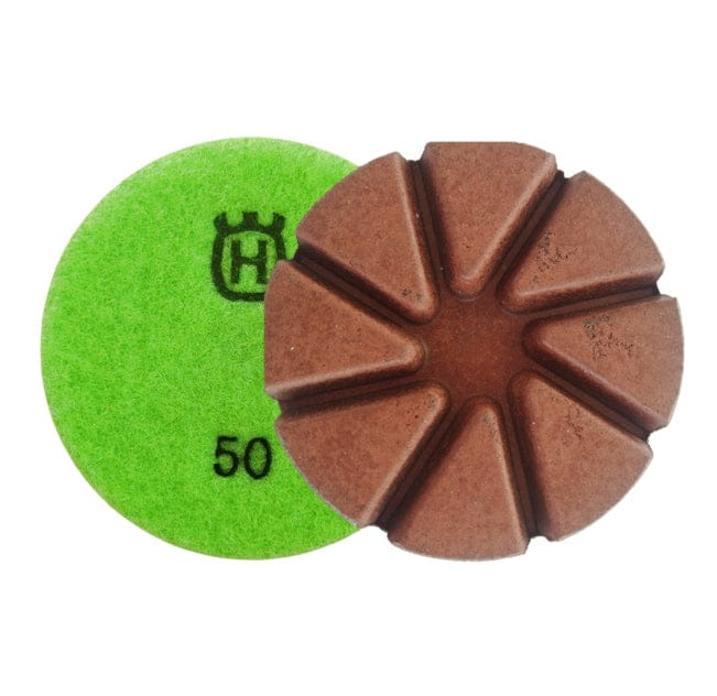 Husqvarna 3-inch 50 grit copper transitional polishing pad set, featuring one green pad labeled “50” with crown logo and one brown segmented pad with radial grooves. Designed for PG grinders, these OEM T60 Series pads are used for concrete scratch removal and resin surface preparation in flooring and stone fabrication applications