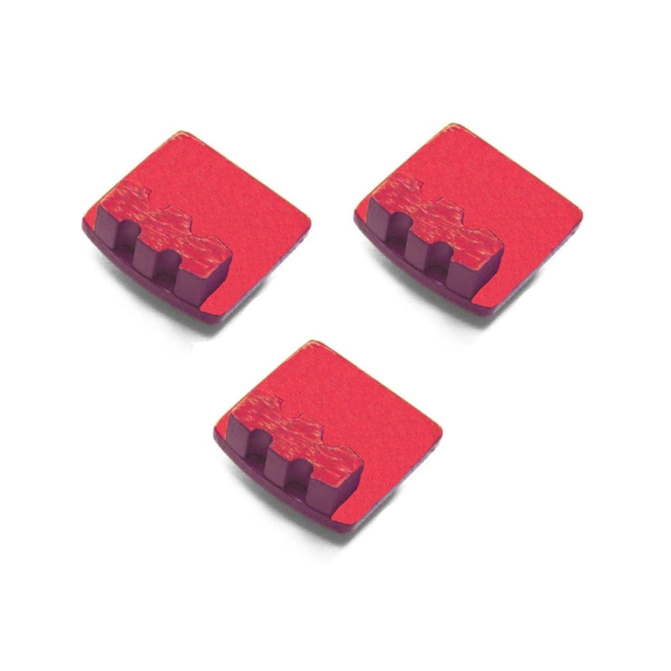 Three red Husqvarna single-segment diamond grinding tools with raised ridges on rectangular bases; designed for soft concrete coating removal.