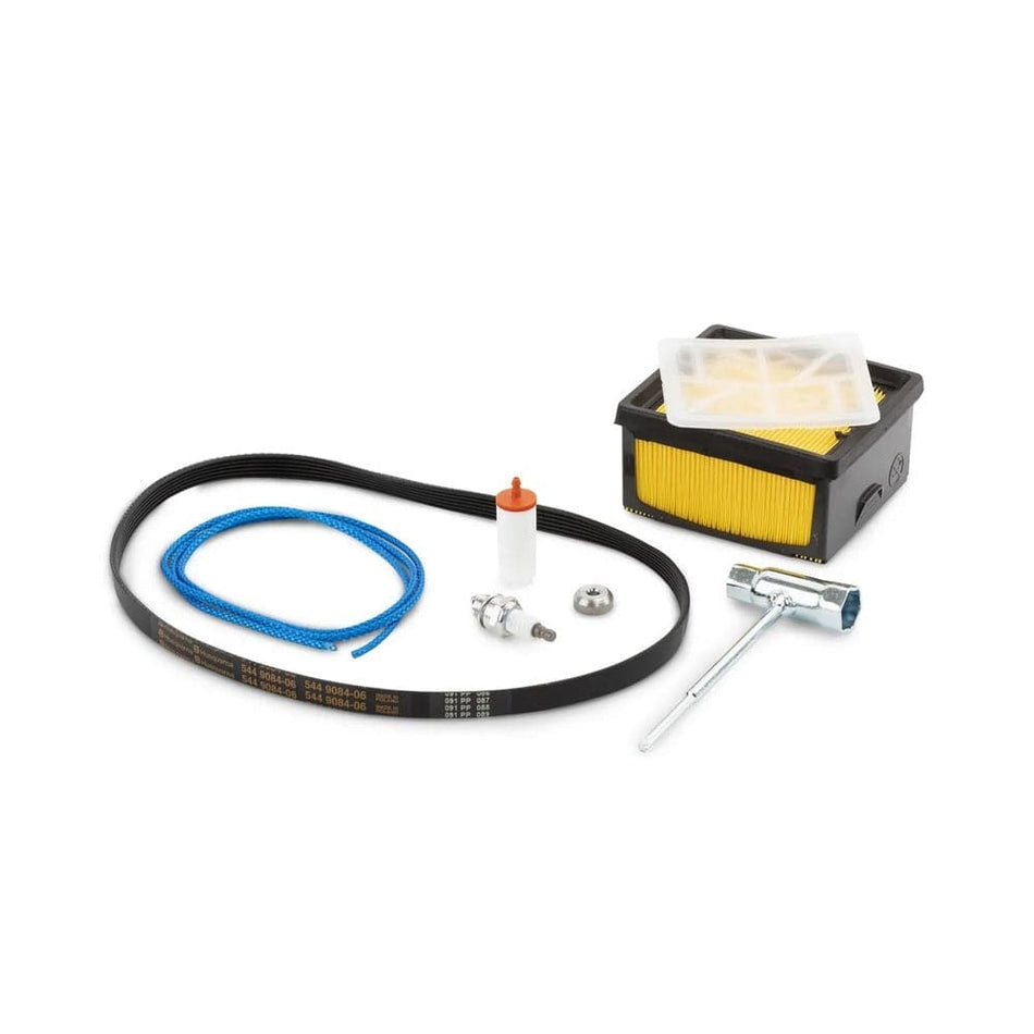A complete Husqvarna K770 service kit displayed on a white background. Includes a black rubber drive belt with white and orange markings, a blue starter cord, a spark plug, an orange-topped cylindrical fuel filter, a metal washer, a spark plug wrench, and a rectangular yellow pleated air filter housed in a translucent plastic cover. These components are arranged neatly and designed for routine maintenance of 12" and 14" Husqvarna cutoff saws