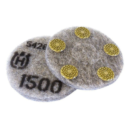 Circular Husqvarna polishing pads shown side by side. One pad features four yellow resin-bonded abrasive segments arranged in a square pattern for surface contact. The other pad displays printed markings including a stylized "H" logo, the number "1500" indicating grit size, and the code "542". Both pads are designed for dry polishing of concrete and terrazzo surfaces using compatible floor grinding machines