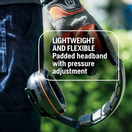 A close-up photo of a gloved hand holding the Husqvarna hearing protectors, highlighting the lightweight and flexible padded headband with pressure adjustment.