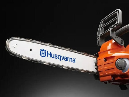 Side profile of the Husqvarna 535i XP guide bar and chain assembly with the inertia-activated chain brake handle and orange motor housing visible in the background.