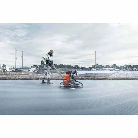 Professional contractor operating the Husqvarna CT 36 walk-behind power trowel on a large-scale concrete pour, demonstrating the tool's effectiveness for high-production concrete finishing and burnishing.
