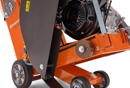 A detailed view of the belt assembly connecting the Honda engine's pulley to the blade housing on the orange frame of the concrete saw.