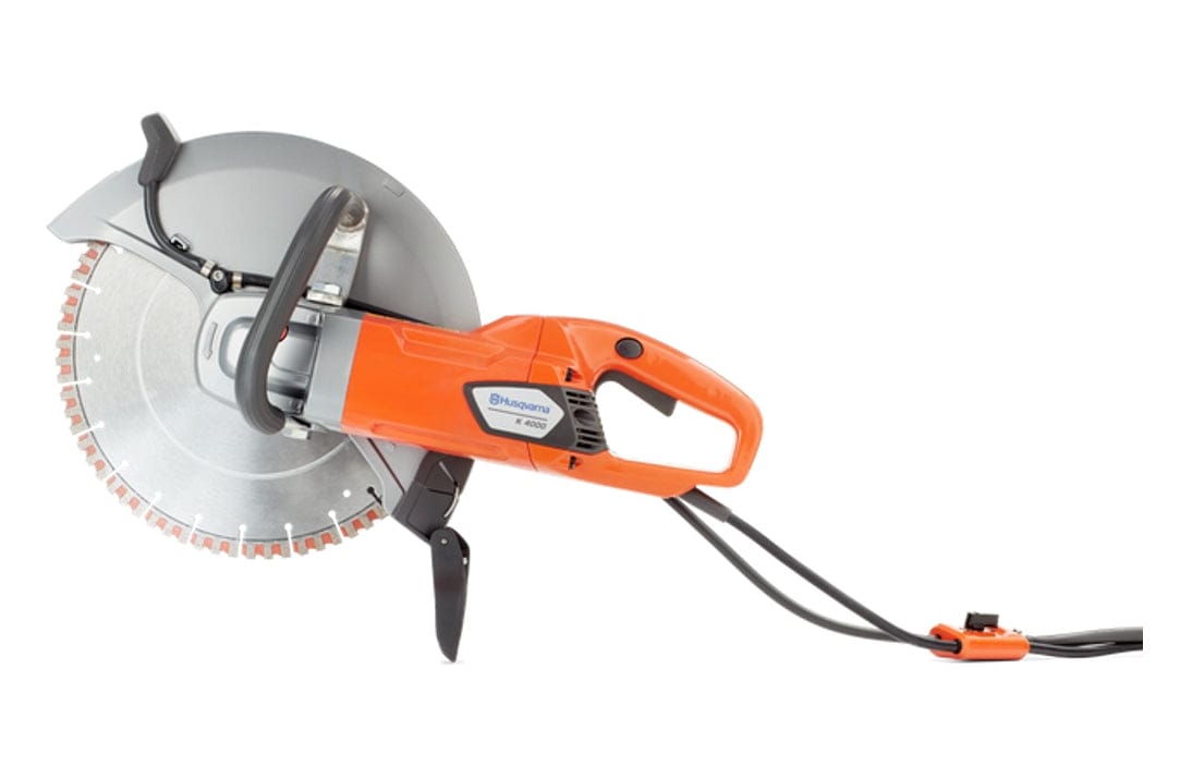 Side profile of the orange and gray Husqvarna K4000 electric power cutter with a diamond blade installed. The handle, cord, and water control valve are visible.