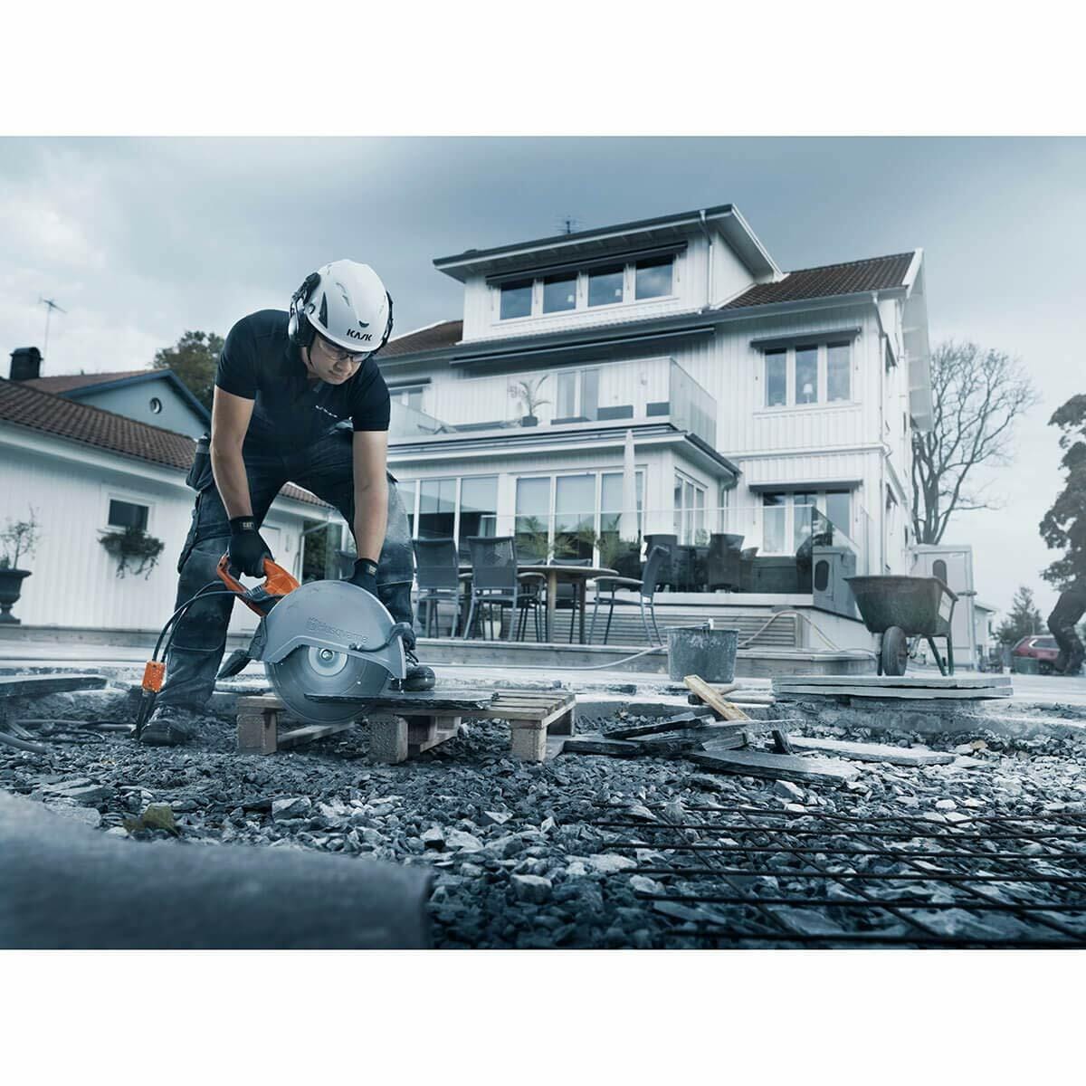 A construction worker uses the Husqvarna K4000 electric power cutter on an outdoor worksite surrounded by debris, emphasizing its heavy-duty cutting capability.