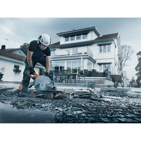 A construction worker uses the Husqvarna K4000 electric power cutter on an outdoor worksite surrounded by debris, emphasizing its heavy-duty cutting capability.