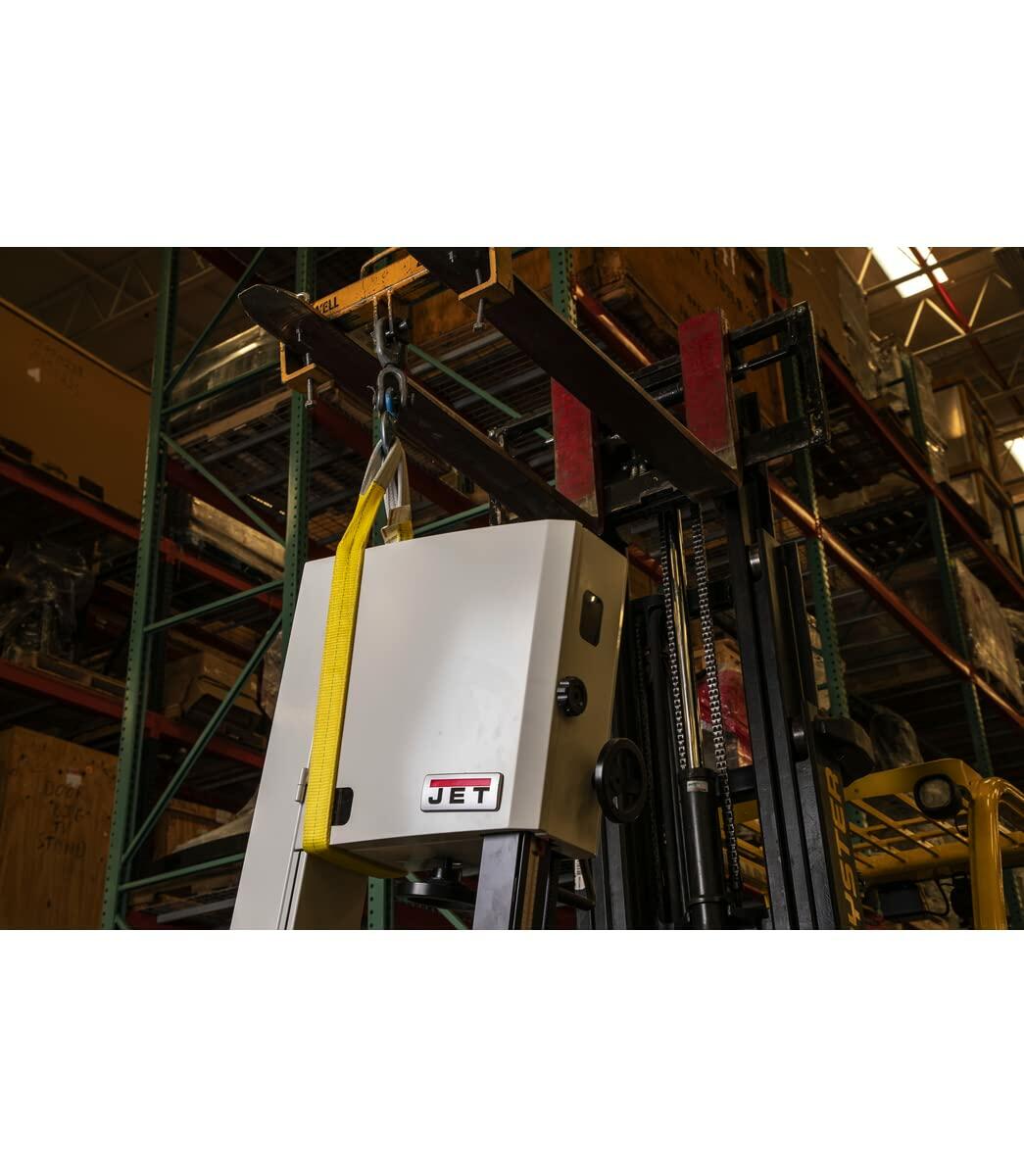 A yellow JET polyester web sling attached to a forklift's lifting accessory, being used to lift a piece of JET machinery in a warehouse environment.