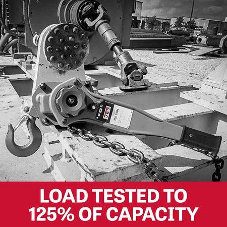 Black and white photo of the lever hoist anchored to heavy machinery, highlighting that the unit is load tested to 125 percent of capacity.