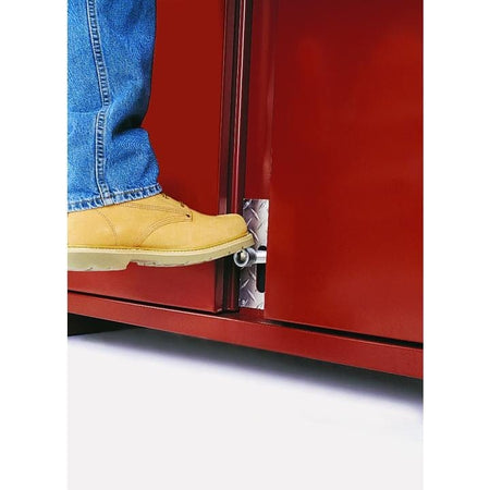 Person wearing work boots activates a foot-operated latch at the base of a red JOBOX cabinet door, demonstrating hands-free access.