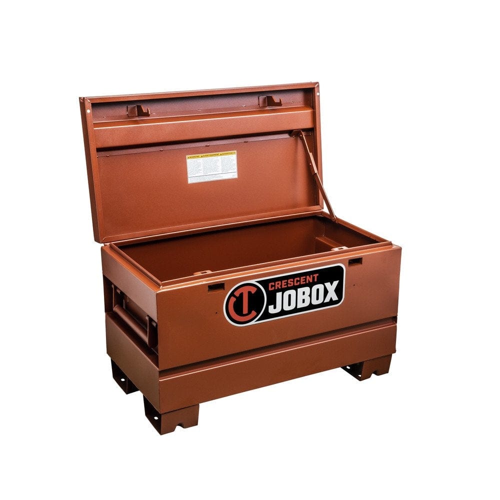 A Crescent JOBOX 36-inch Tradesman steel jobsite chest, closed, in a brown powder-coated finish, shown in a work area with other construction supplies.