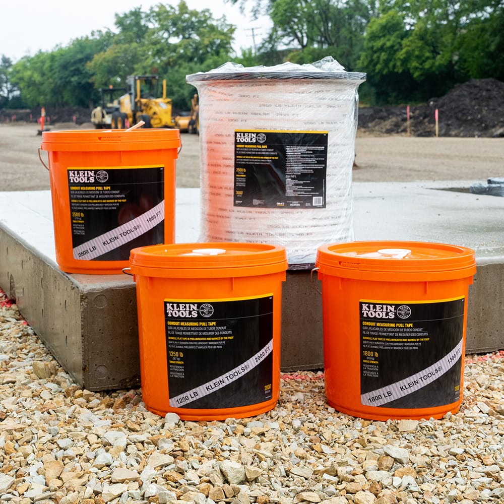 Klein Tools conduit pull tape product family showing 1250 lb, 1800 lb, and 2500 lb tensile strength options in buckets and large jobsite reels.
