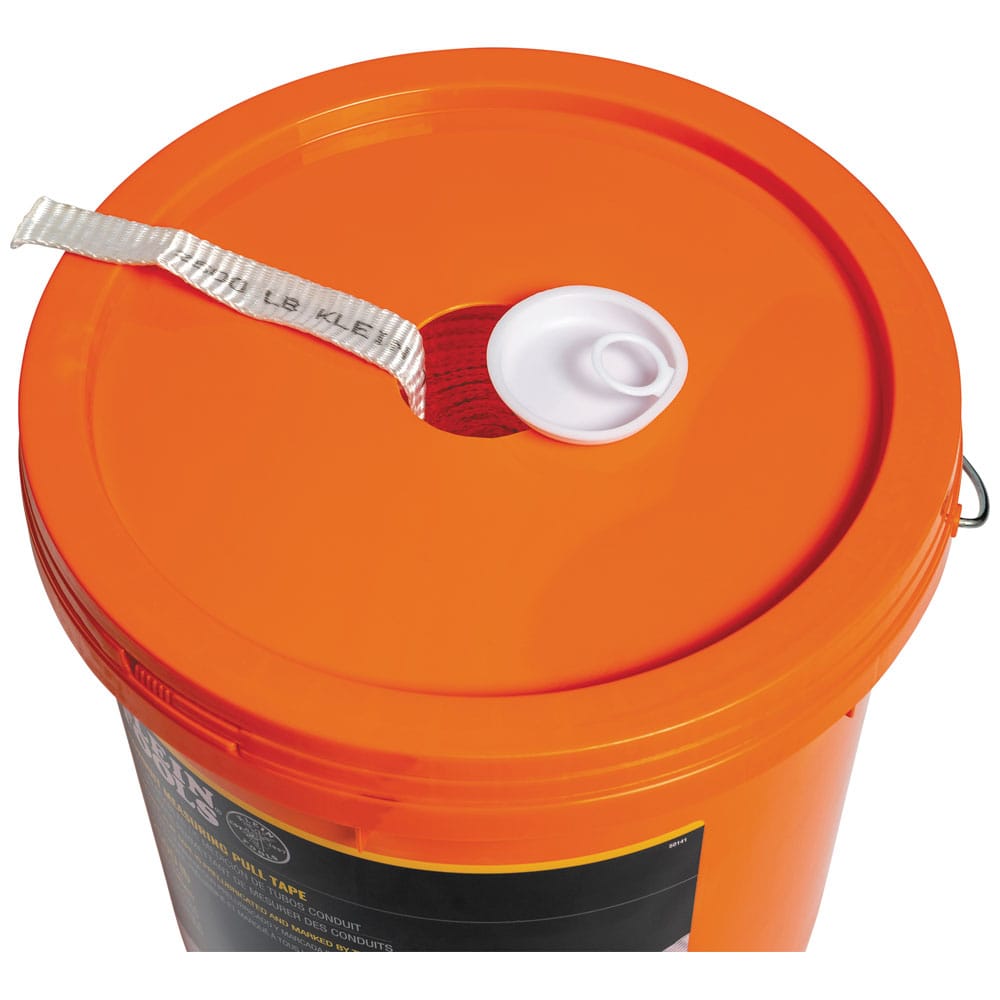 Top-down view of the Klein 50141 orange bucket lid showing the white cap removed from the center hole for pre-lubricated tape feed.