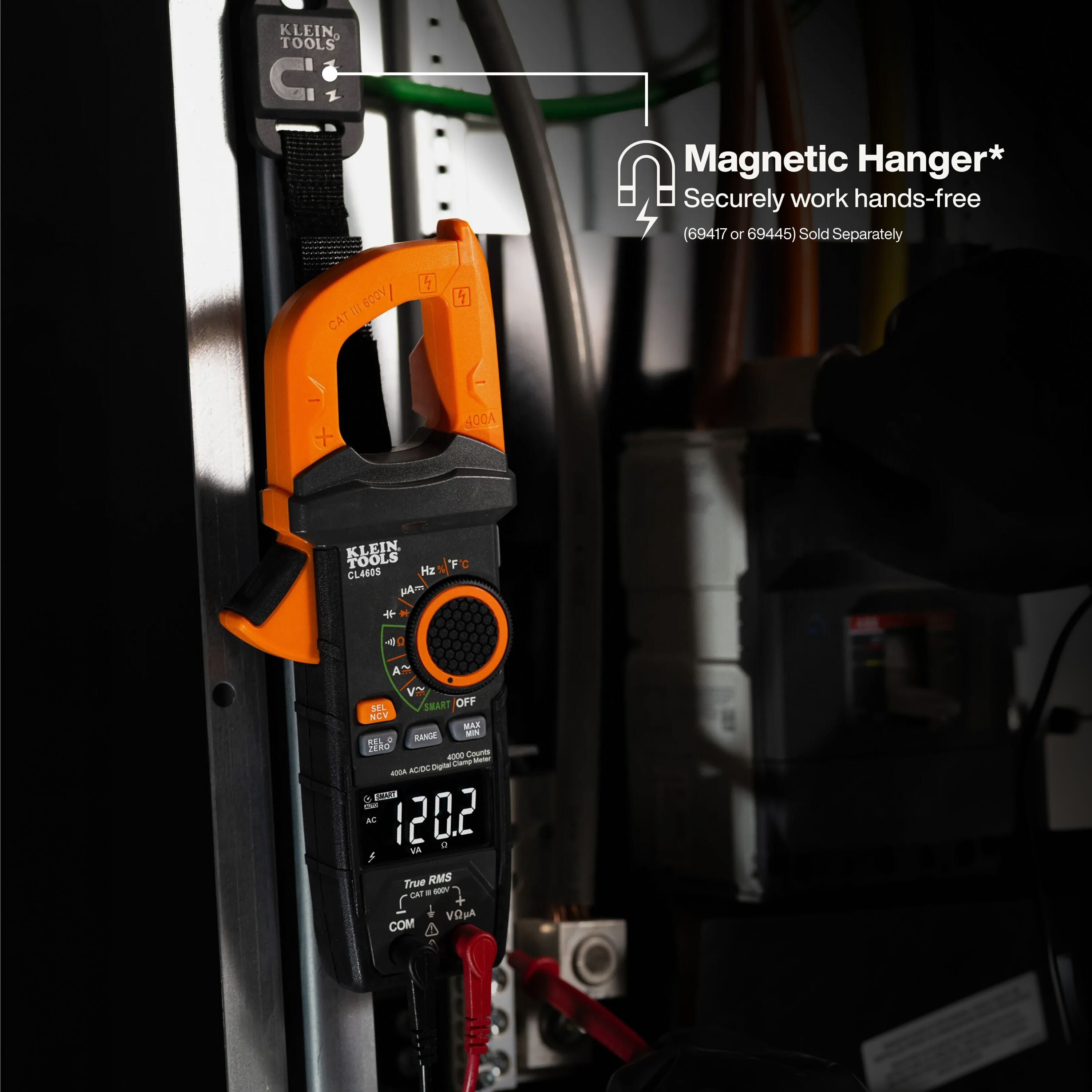 Klein CL460S clamp meter mounted hands-free on a metal electrical cabinet door using an optional magnetic hanging strap for panel testing.