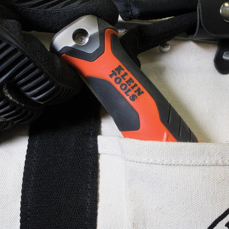 The Klein folding jab saw is shown folded and tucked into the pocket of a canvas tool bag.