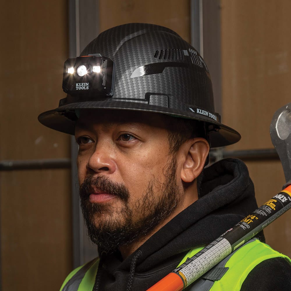 Close-up of a worker wearing the non-vented Klein Tools hard hat with the attached LED headlamp providing hands-free work light.