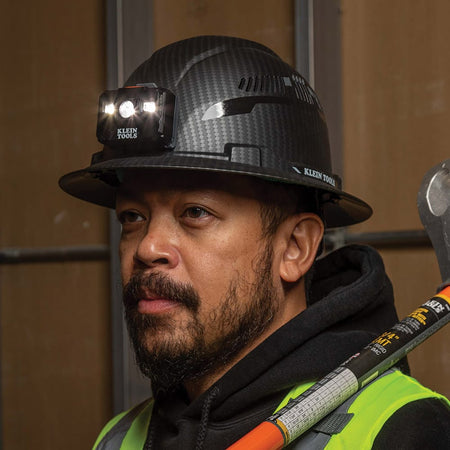 Close-up of a worker wearing the non-vented Klein Tools hard hat with the attached LED headlamp providing hands-free work light.