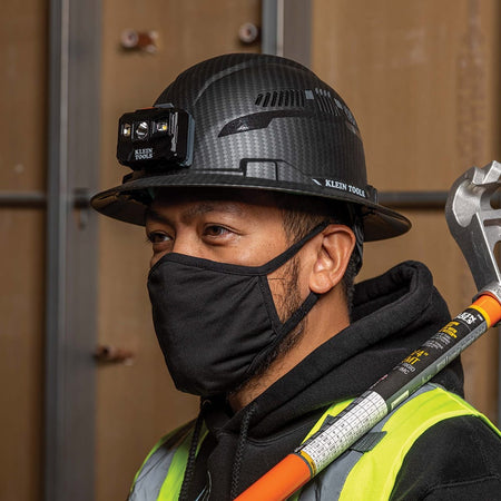 Close-up of a worker wearing the ventilated Klein Tools hard hat with the attached LED headlamp providing hands-free work light