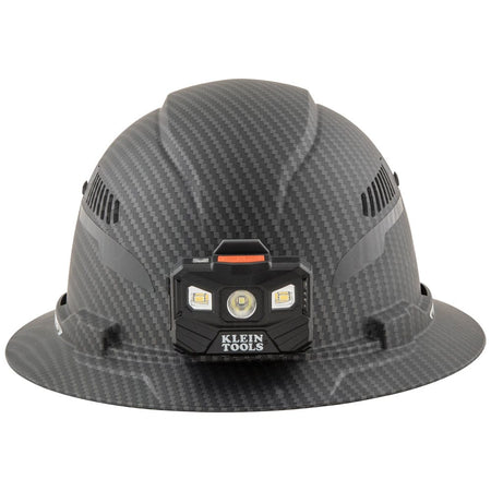 Front view of Klein Tools KARBN vented hard hat with attached 400-lumen LED headlamp providing hands-free work illumination.