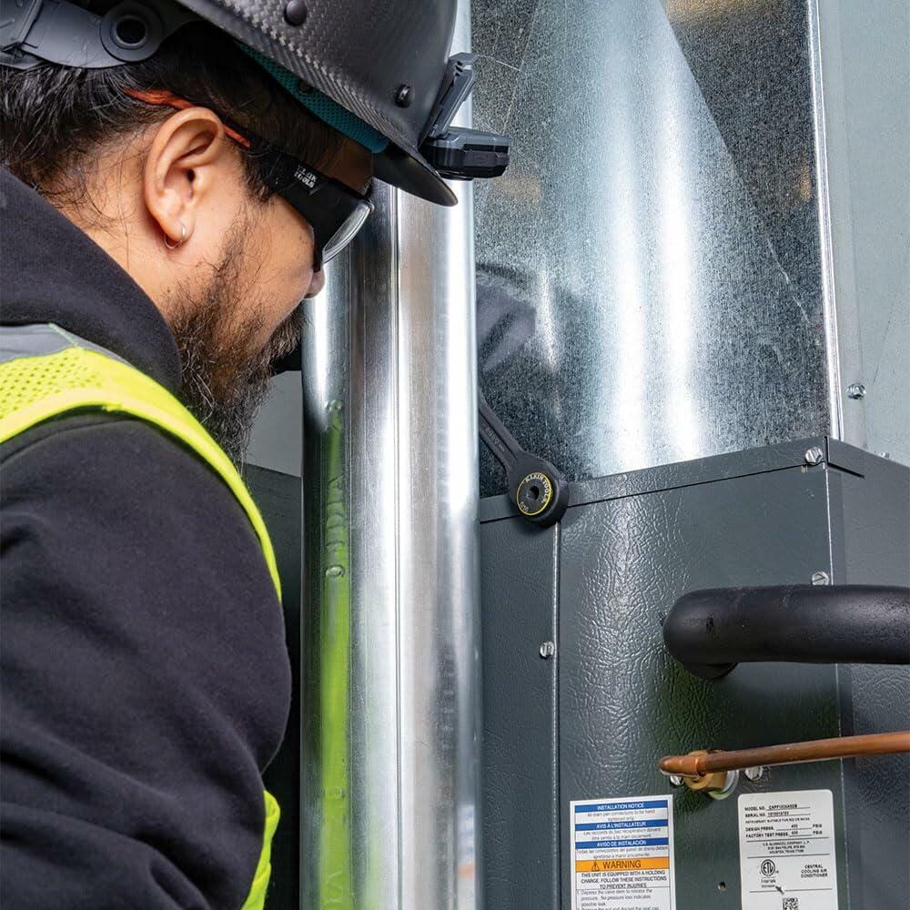 Close-up of a worker in safety gear using the KNECT Pass-Through Ratchet on a furnace or HVAC unit, demonstrating use of the tool in a confined area.
