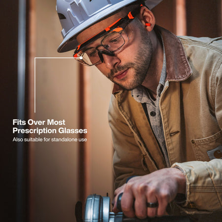 Action shot of a professional tradesman using a power tool while wearing the 03006 safety glasses comfortably over his prescription eyewear, demonstrating the versatile OTG and standalone fit.
