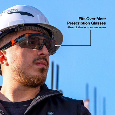 Action shot of a professional worker outdoors wearing the 03007 shaded safety glasses over his prescription eyewear, demonstrating the comfortable OTG fit for bright construction environments.