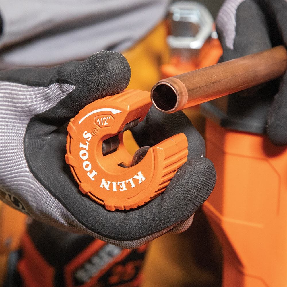 An image of the Klein Tools 50055 being held next to a freshly cut copper pipe with clean, straight edges. This highlights the high-precision results of the C-style cutter compared to traditional methods in plumbing and HVAC repair.