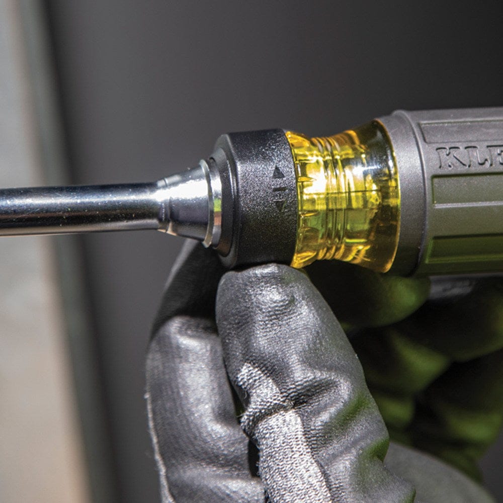 Close-up of a gloved hand adjusting the black ratcheting collar on the screwdriver to change the driving direction.