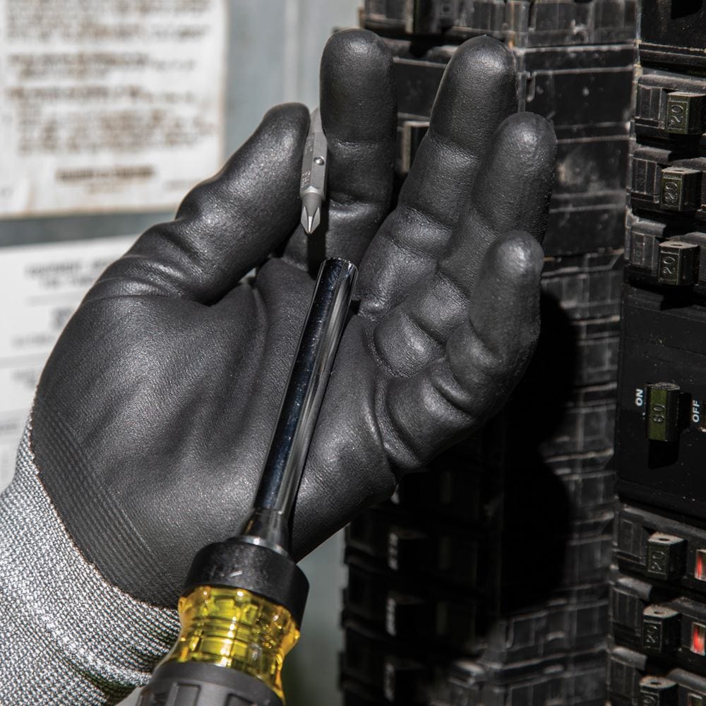 A gloved hand holding the screwdriver shaft and a detached double-ended bit, preparing to insert the bit into the holder.