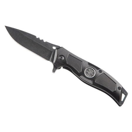 Klein Tools 44228R electrician folding pocket knife shown fully deployed at an angle on a white background, highlighting its black finish stainless steel drop point blade, spine stripping notches, integrated wire looping hole, flipper lever, and a rugged black aluminum handle complete with a circular brand logo.