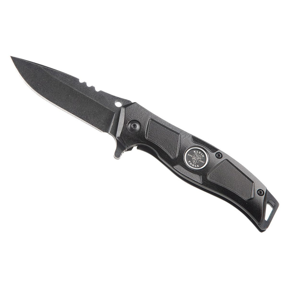 Klein Tools 44228R electrician folding pocket knife shown fully deployed at an angle on a white background, highlighting its black finish stainless steel drop point blade, spine stripping notches, integrated wire looping hole, flipper lever, and a rugged black aluminum handle complete with a circular brand logo.