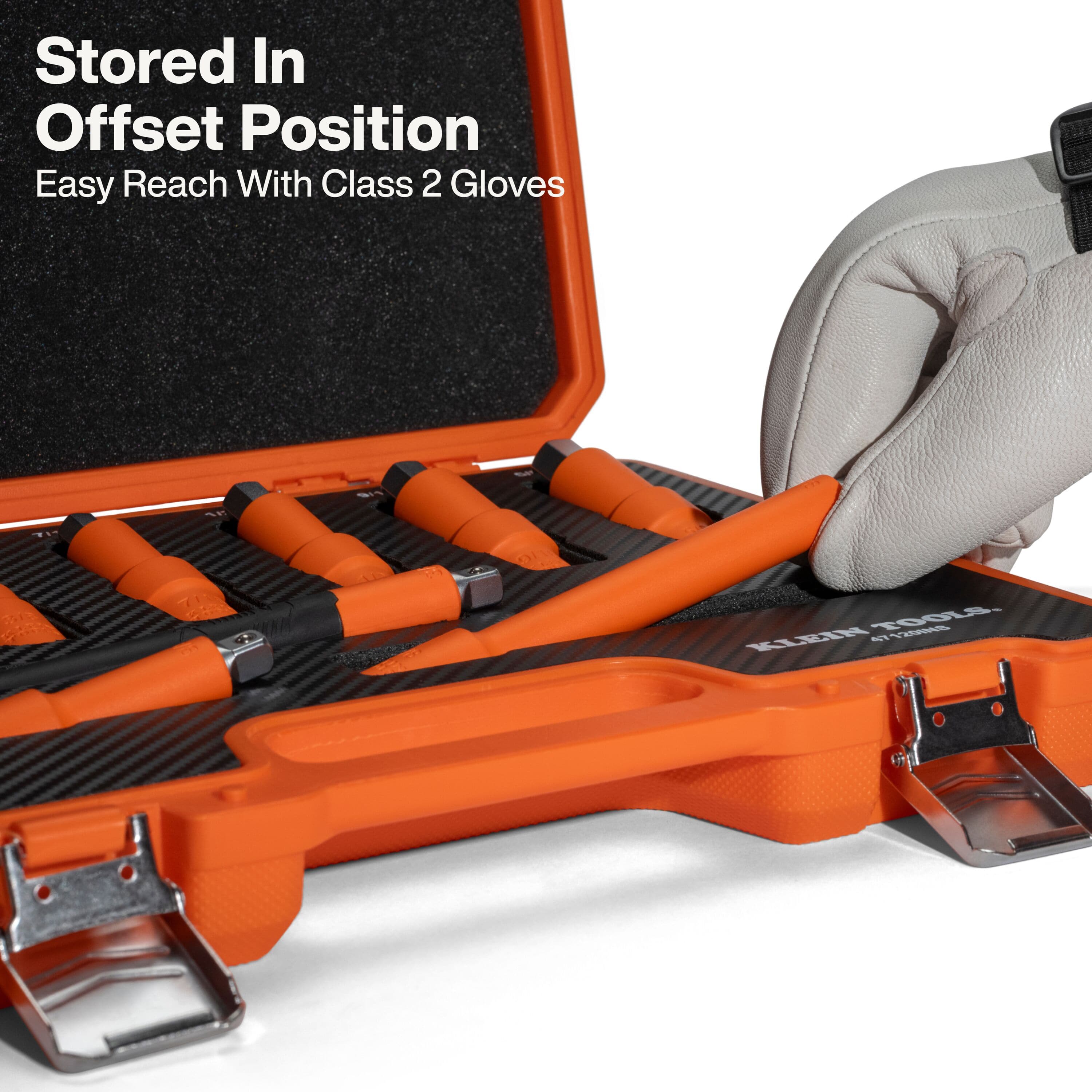 Detailed view of a hand in a Class 2 glove retrieving an insulated extension bar from its offset storage position in the foam case, highlighting the design for easy access while wearing bulky safety equipment.