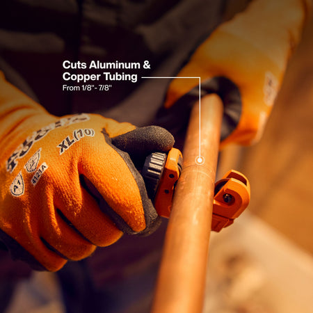 A professional tradesman using the micro tubing cutter to score a copper pipe, illustrating the tool's compact 1/8-inch to 7/8-inch cutting range for precision plumbing installations.