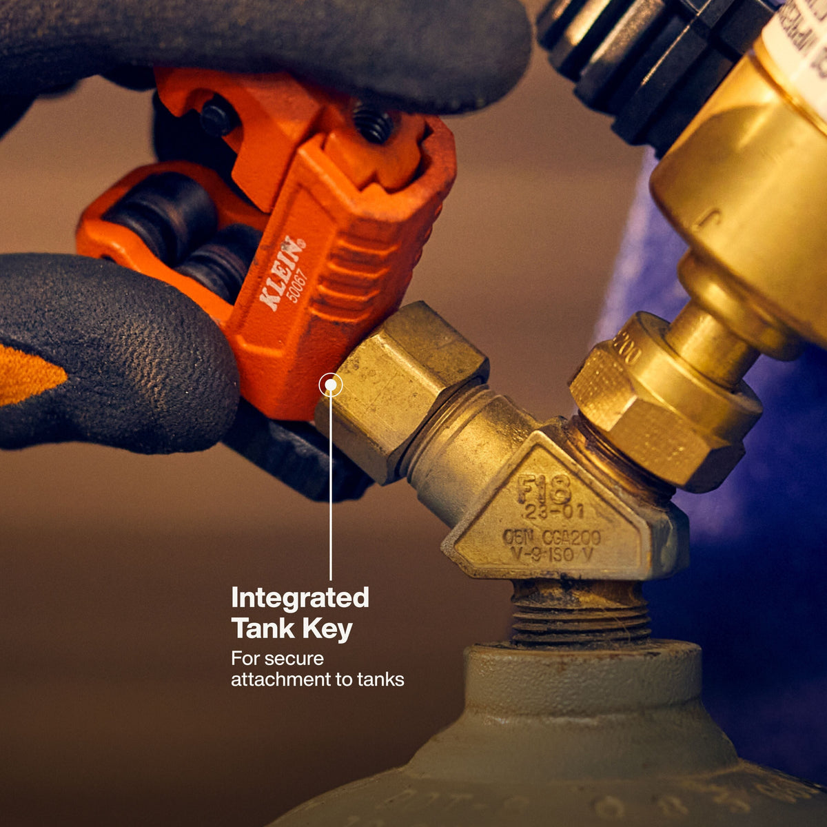 Detailed action shot showing the integrated B tank key on the bottom of the tubing cutter being used to open an acetylene gas tank valve on a professional jobsite.
