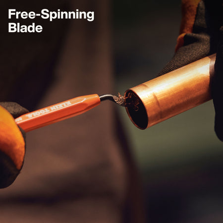 Action shot demonstrating the free-spinning blade of the Klein Tools reaming pen removing metal burrs from the interior rim of a copper pipe.