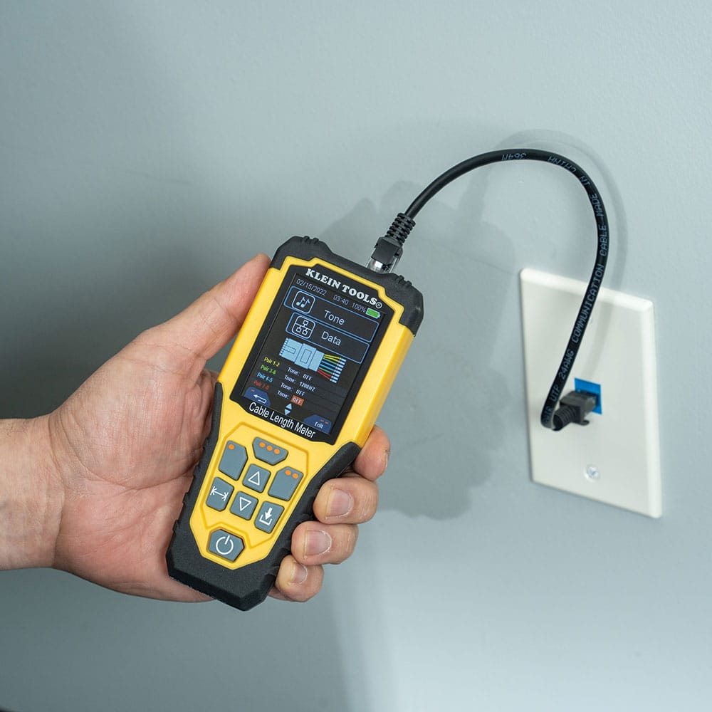 Action shot showing the 501915 meter connected to a standard RJ45 wall jack using an Ethernet patch cable. The device is shown in "Data Tone" mode, illustrating its dual-functionality as both a length meter and a high-performance tone generator for wire tracing.