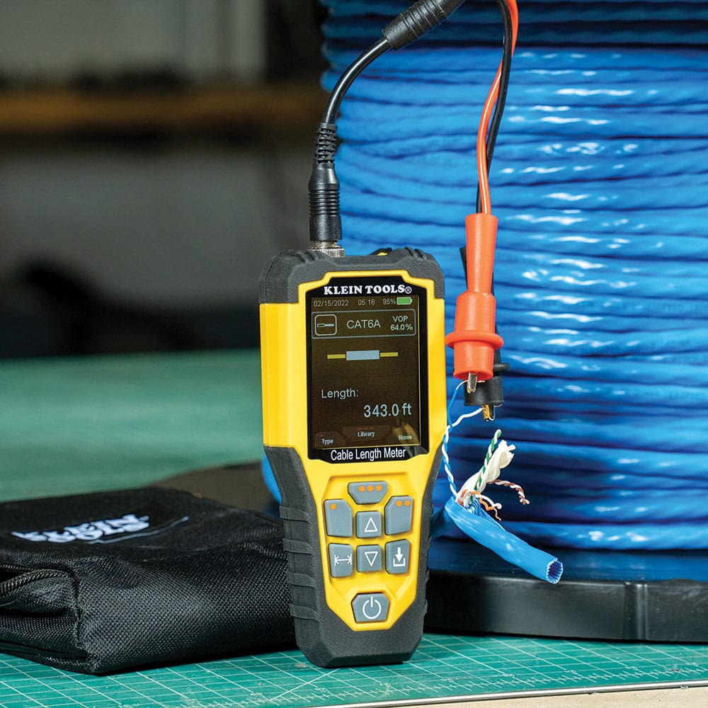 Action shot of the Klein Tools 501915 measuring a large spool of CAT6A cable. The technician uses the heavy-duty alligator clips to connect to the wire pairs, while the meter displays a real-time length measurement of 343.0 feet, facilitating efficient inventory management.