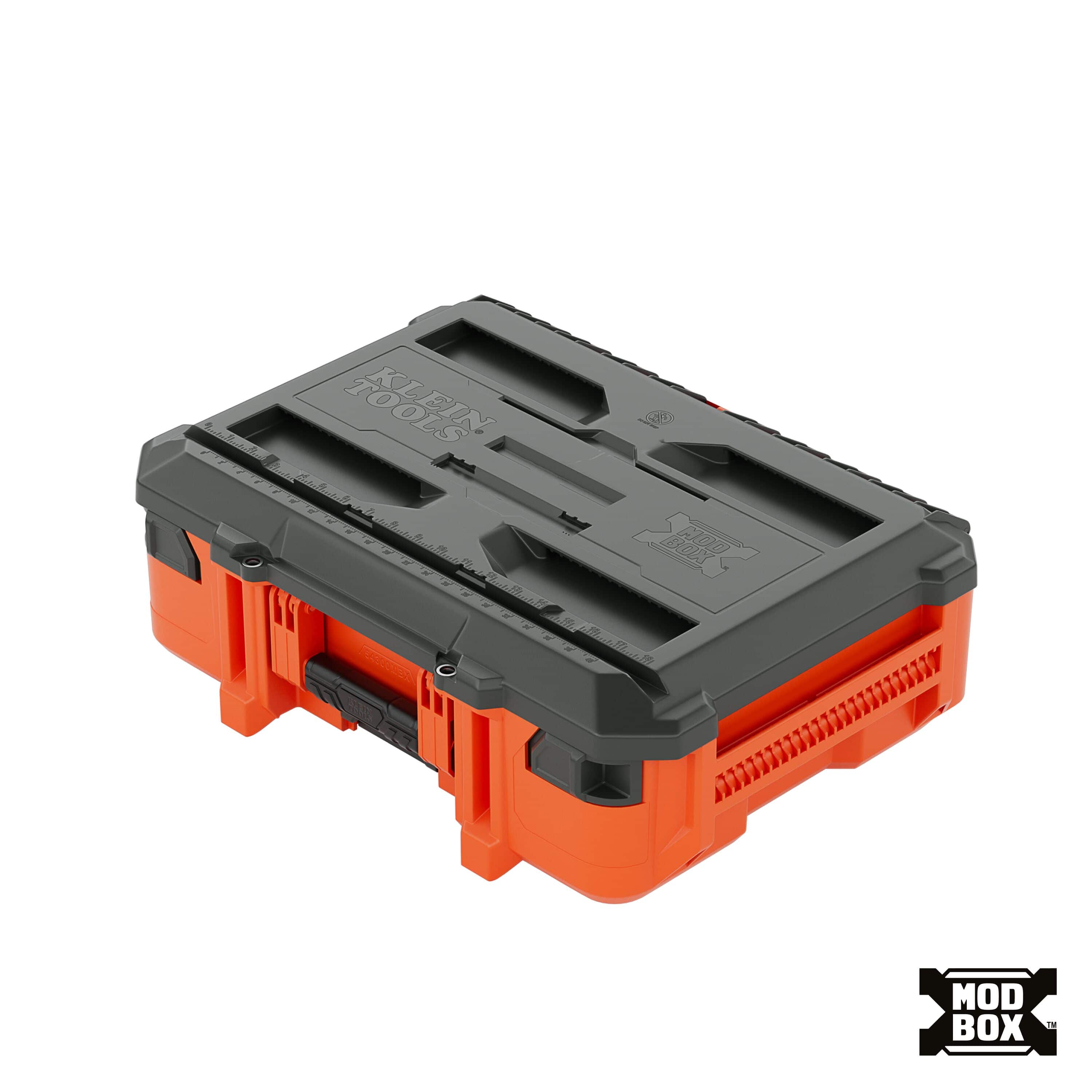 Perspective view of the orange Klein Tools 54300MBX MODbox small toolbox showing the dark grey heavy-duty workstation lid with integrated measuring ruler and side rail system.