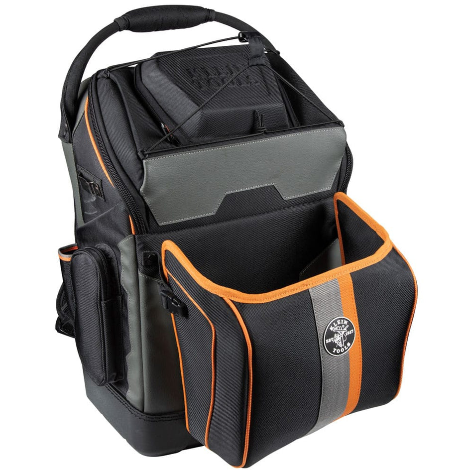 A studio product view of the Klein Tools 55665 Ironworker and Welder Backpack with the front compartment open. The image highlights the specialized removable front pocket designed to hold a welding helmet and hard hat, constructed from black and orange flame-resistant ballistic weave.