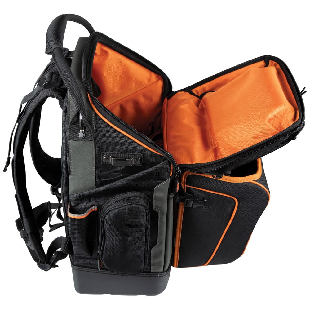 A left-side profile view of the Klein Tools 55665 backpack partially unzipped. This angle showcases the depth of the main compartment, the padded ergonomic shoulder straps, and a side zipper pocket for storing smaller gear or personal items.
