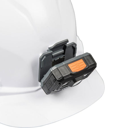 A detailed view of the headlamp being snapped into the front mounting bracket of a white hard hat.