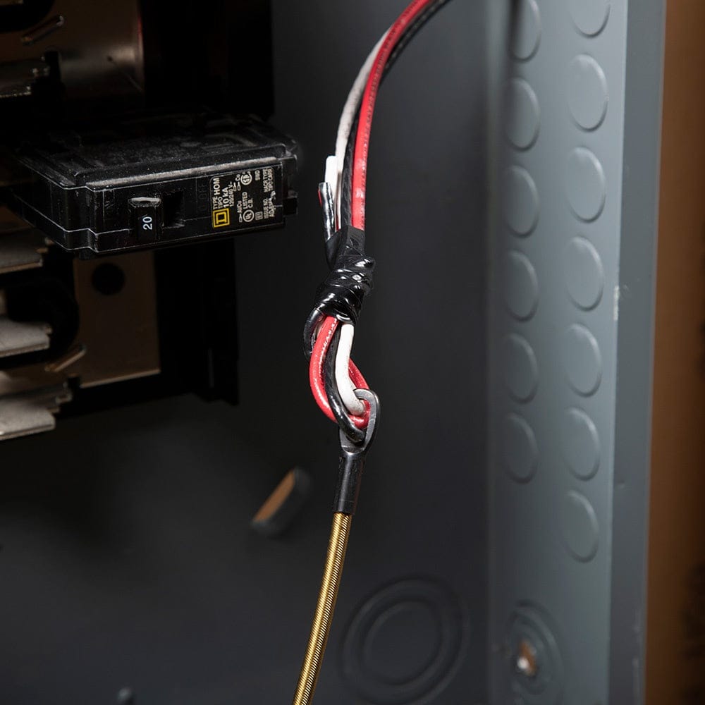 Close-up view inside an electrical panel showing wires secured to the fish tape loop with electrical tape for pulling.