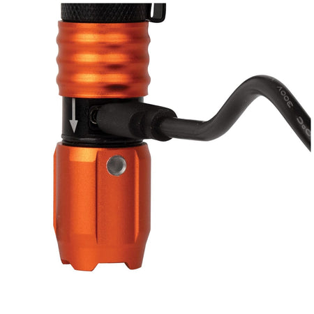 A close-up demonstration of the USB-C charging process, showing the cable securely plugged into the port located beneath the sliding protective collar of the orange and black flashlight.